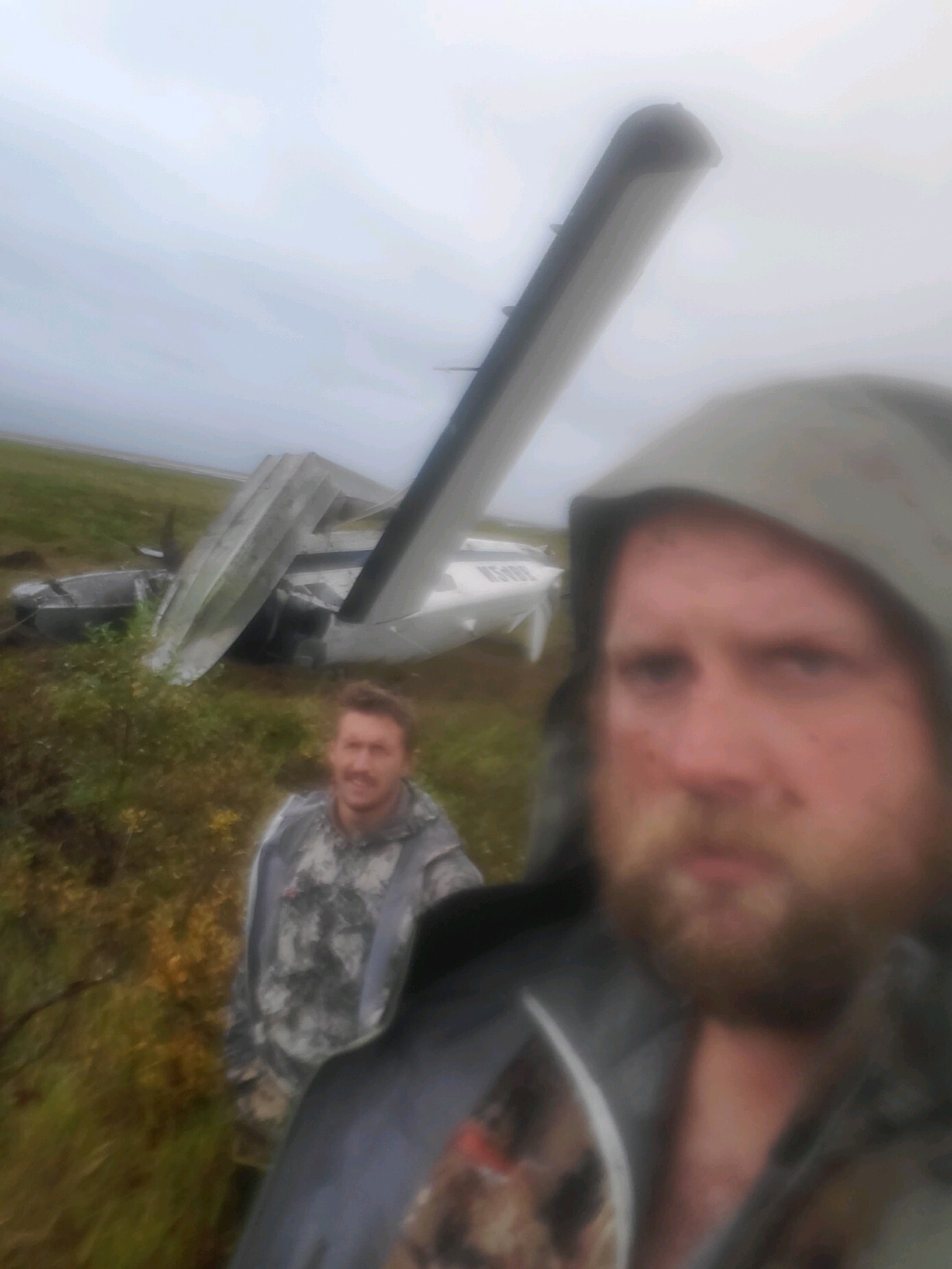two men with plane wreck behind them