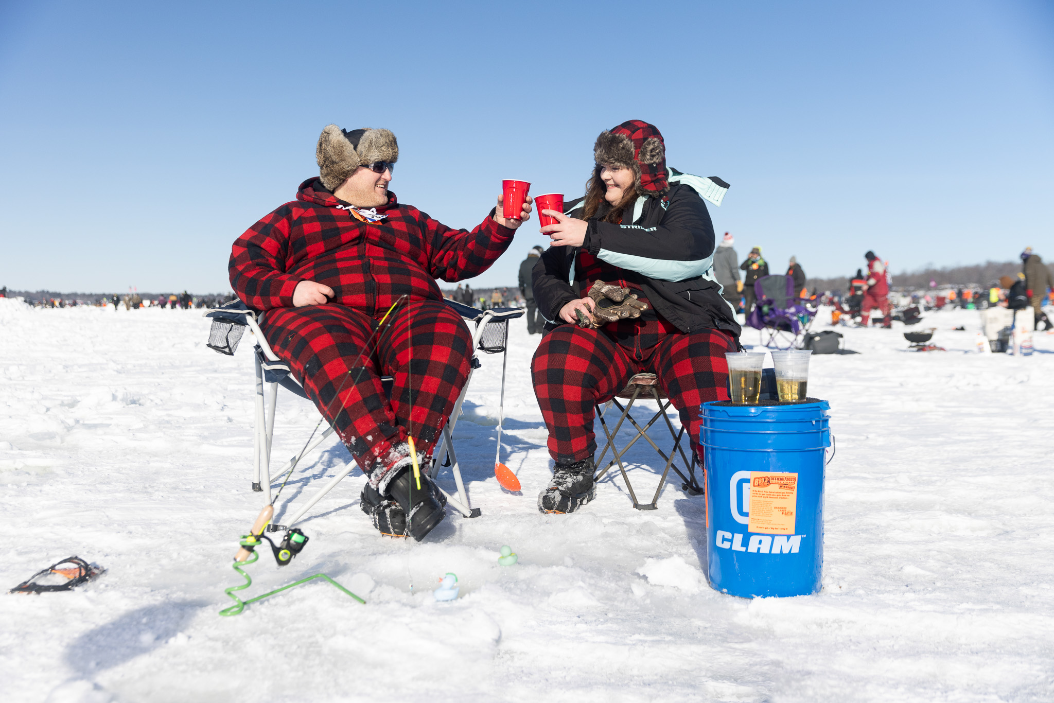 A couple in red buffalo check pajamas toasts each other with a hot chocolate.