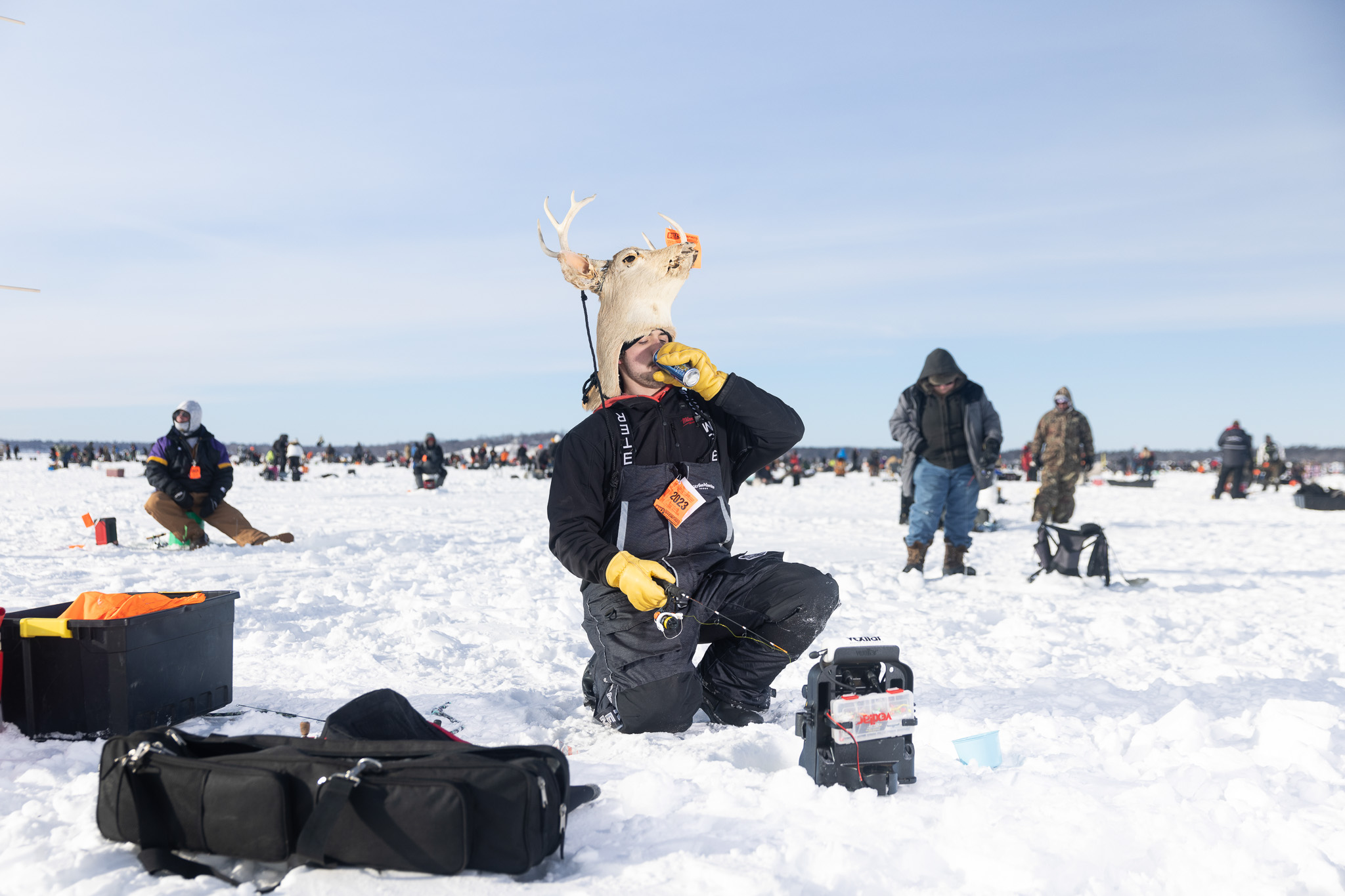 An ice fisherman drinks an energy drink while jigging an ice hole at the ice fishing extravaganza.