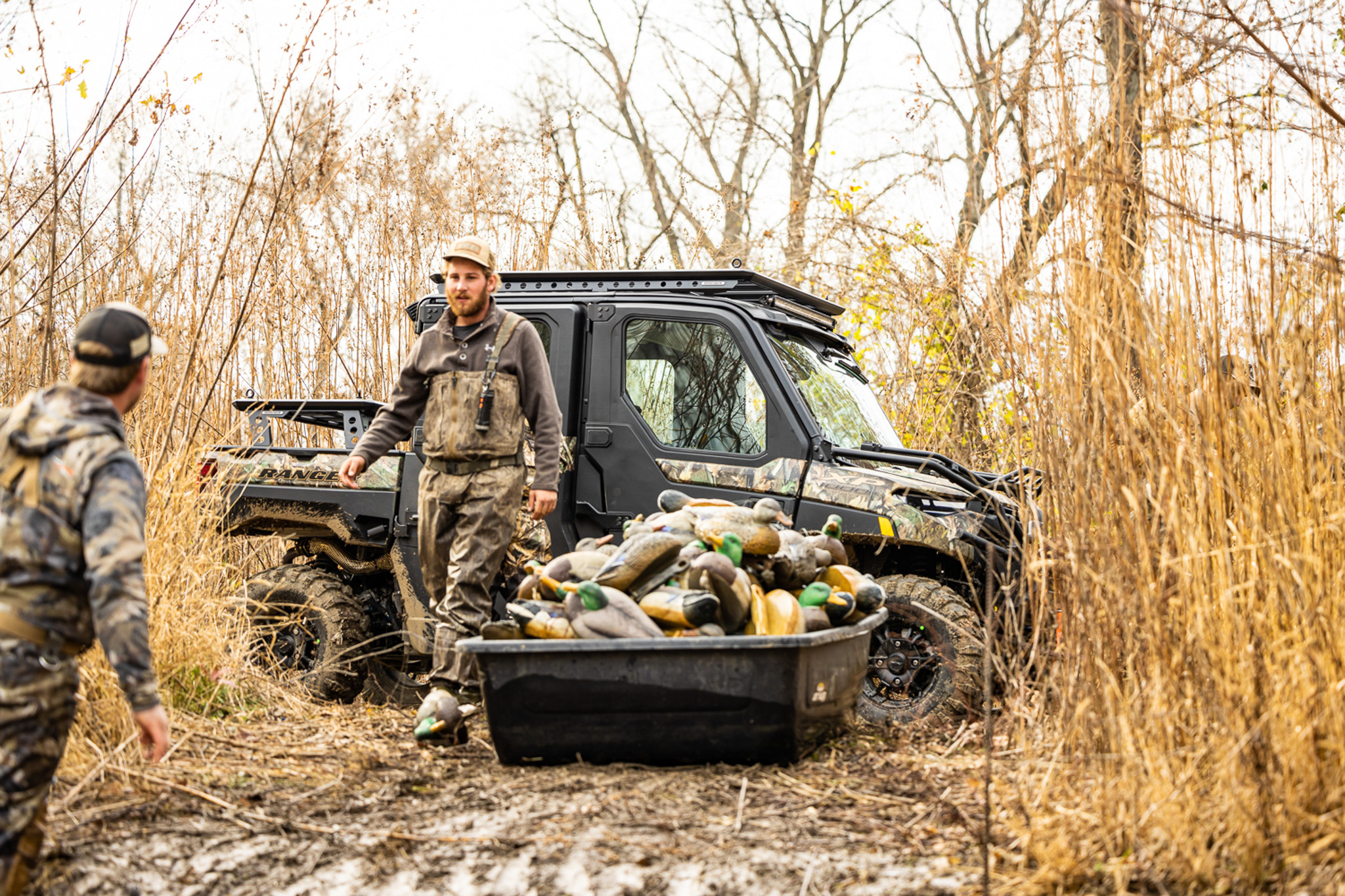 Two hunters with decoys and a Polaris Ranger.