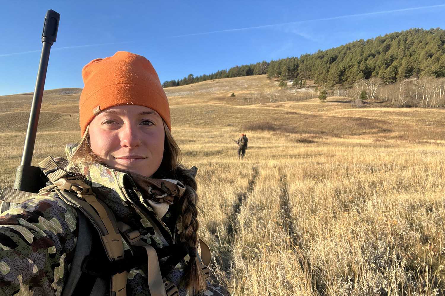 selfie of hunter with two others in distance across meadow