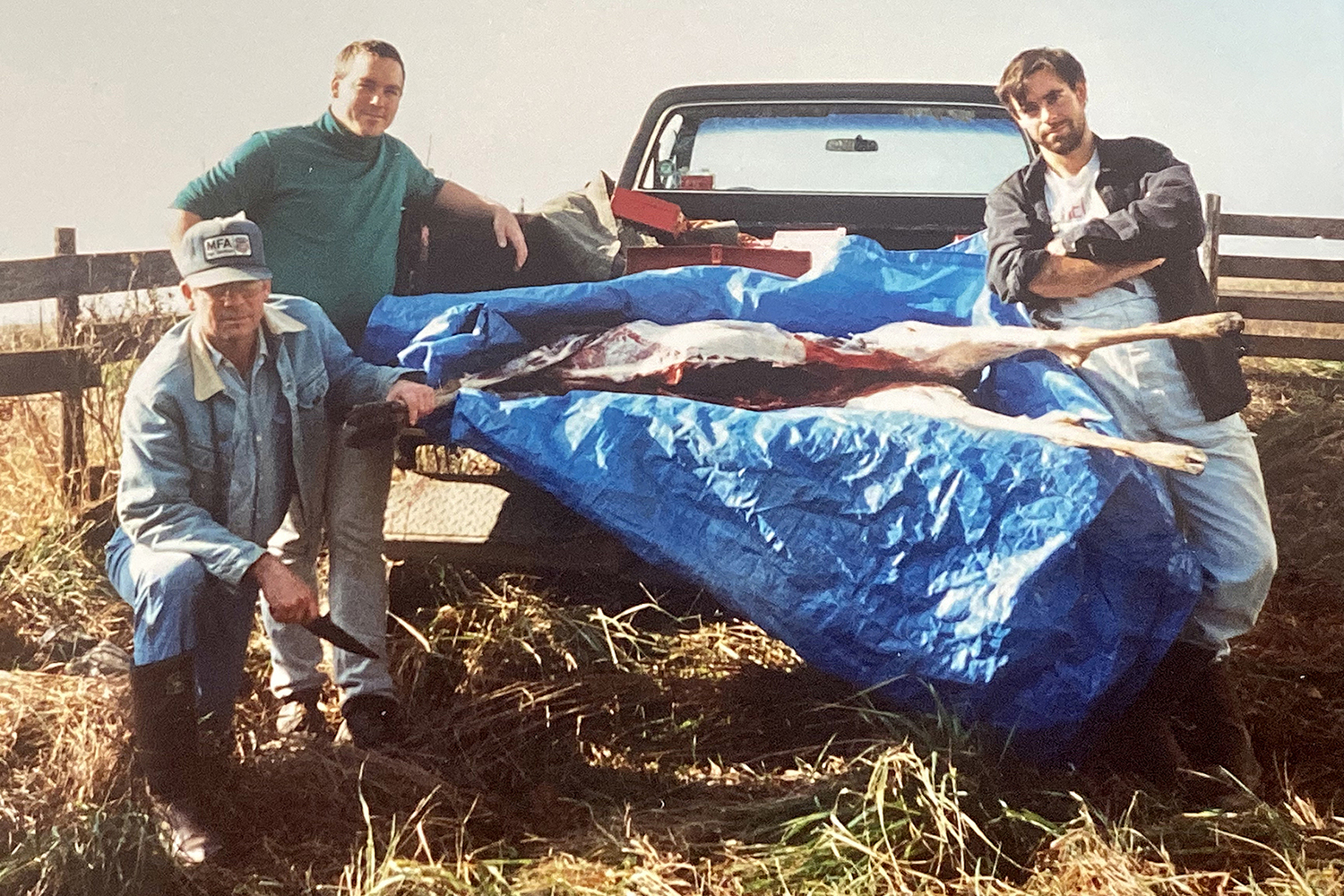 hunters pose around truck bed with deer