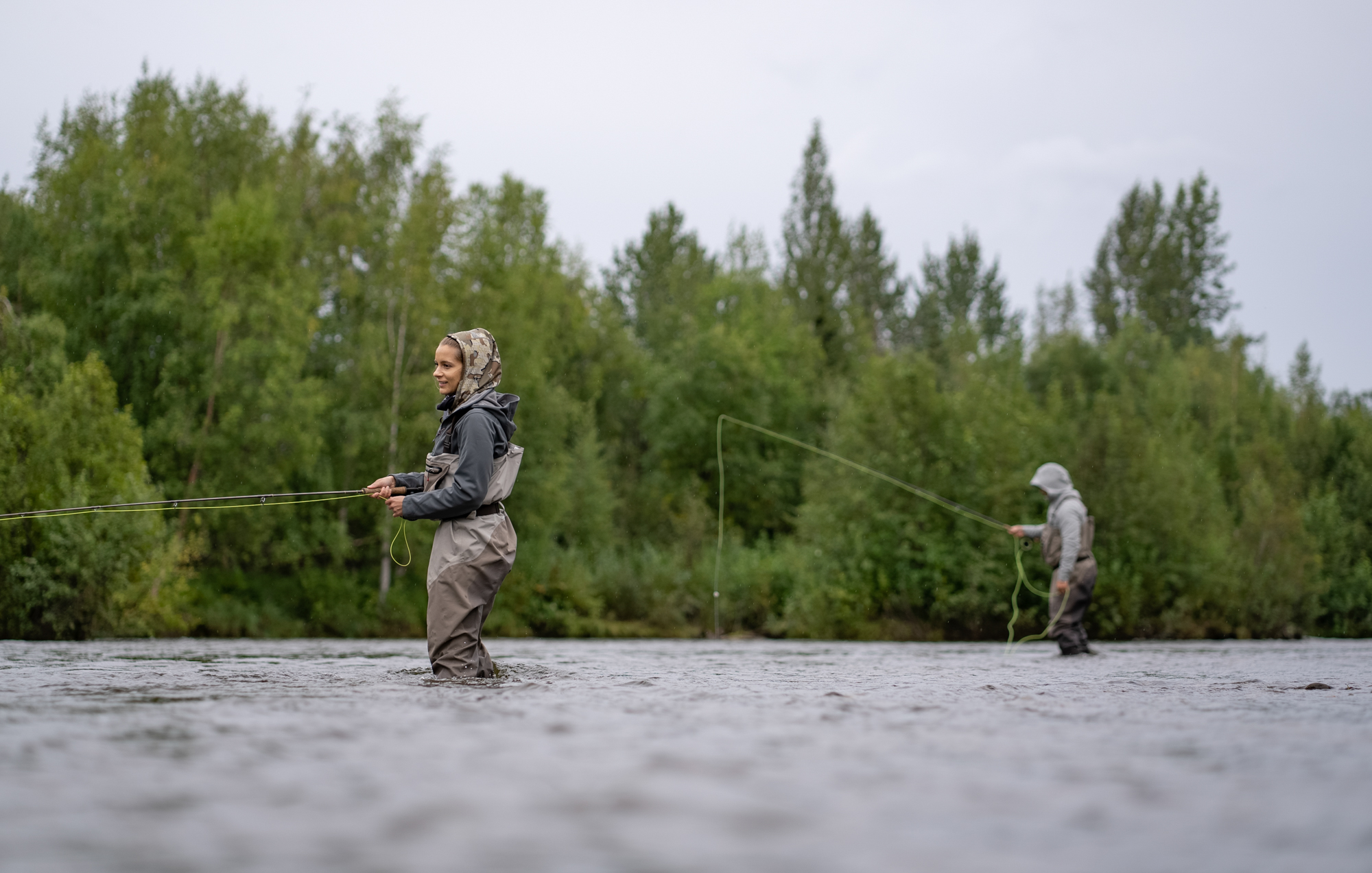 A man and a woman in fishing waders fly fish Willow Creek in Alaska.