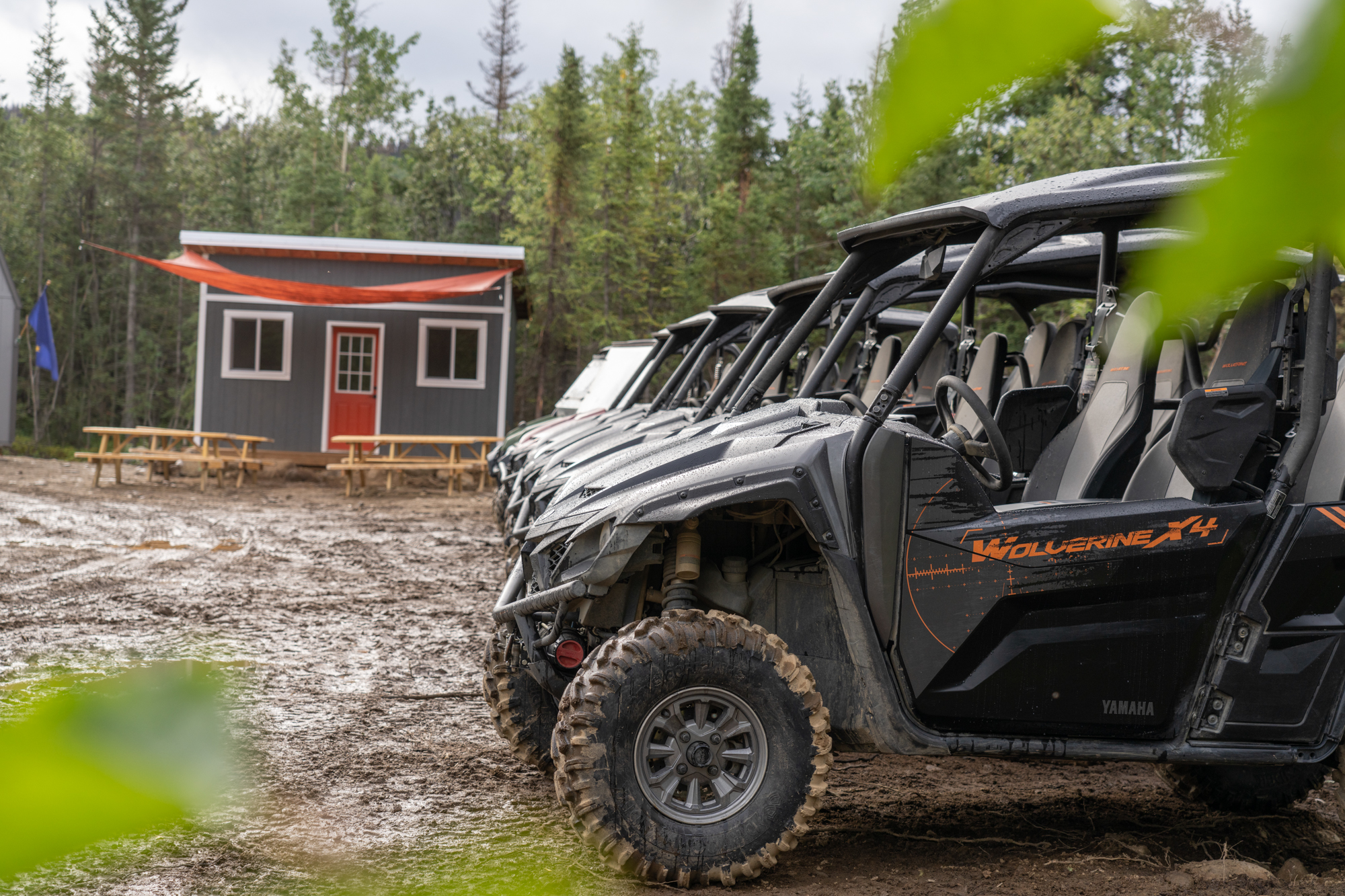 A row of Wolverine UTVs parked in front of a shed.