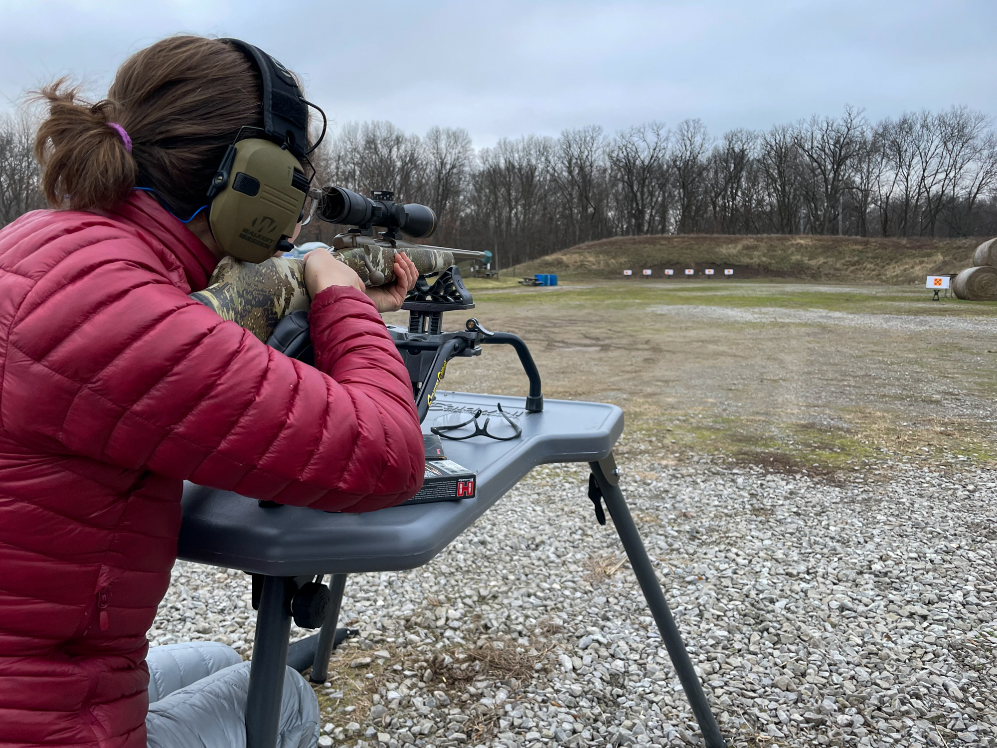 A hunter in a puffy jacket checks the zero of her deer rifle at the range.