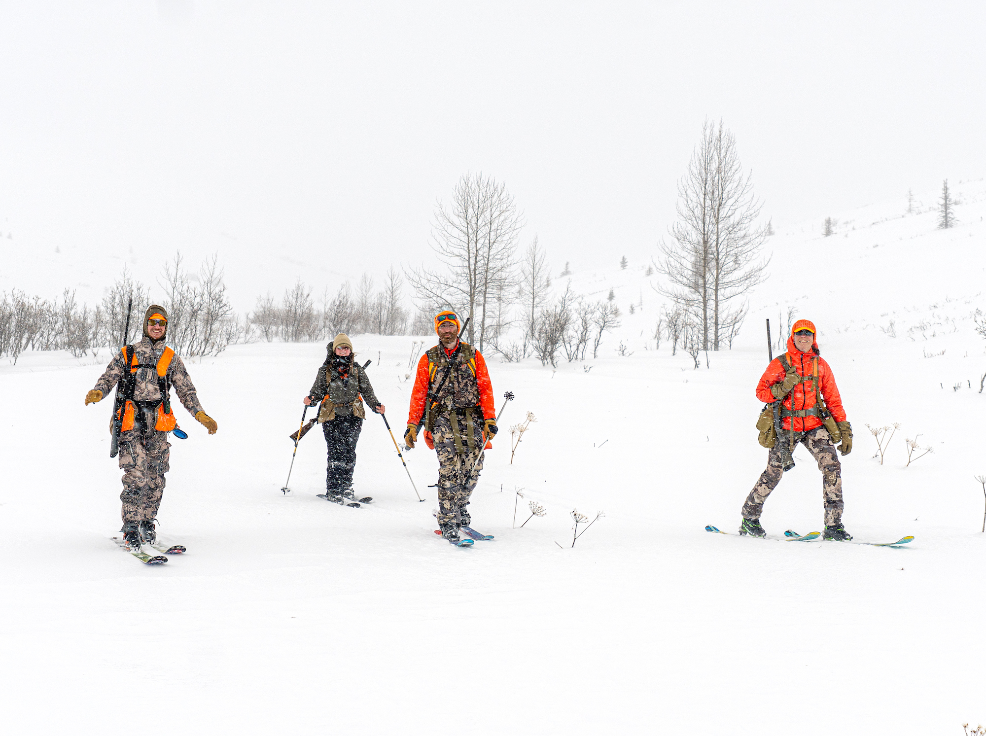 Four bird hunters skiing in the snow.