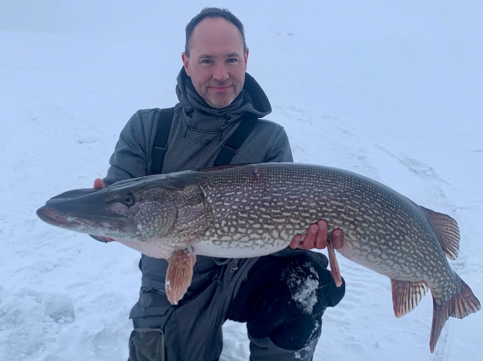 A Wisconsin ice fisherman holds onto a fat Minnesota state-record pike.