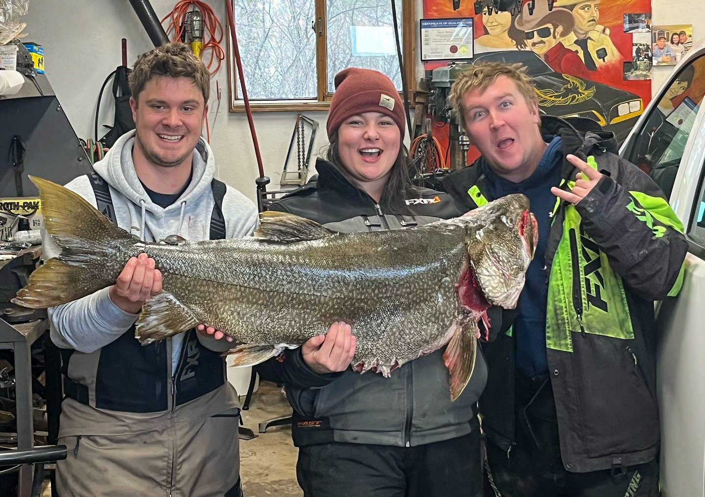 Three anglers hold a giant laker.