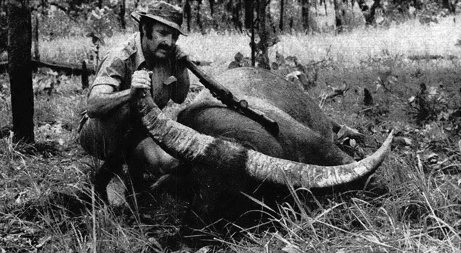 B&W photo of hunter with dead buffalo