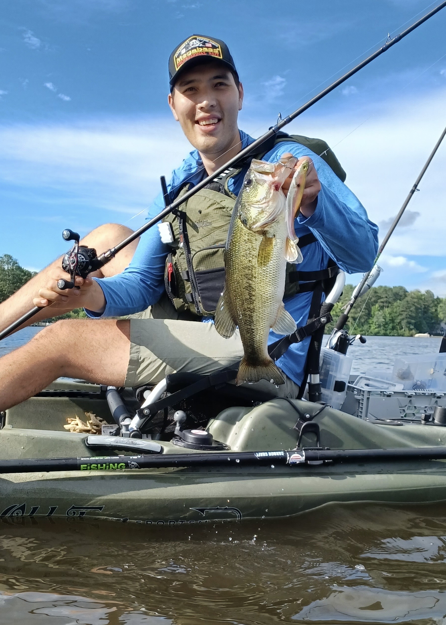 Author holds bass in kayak.
