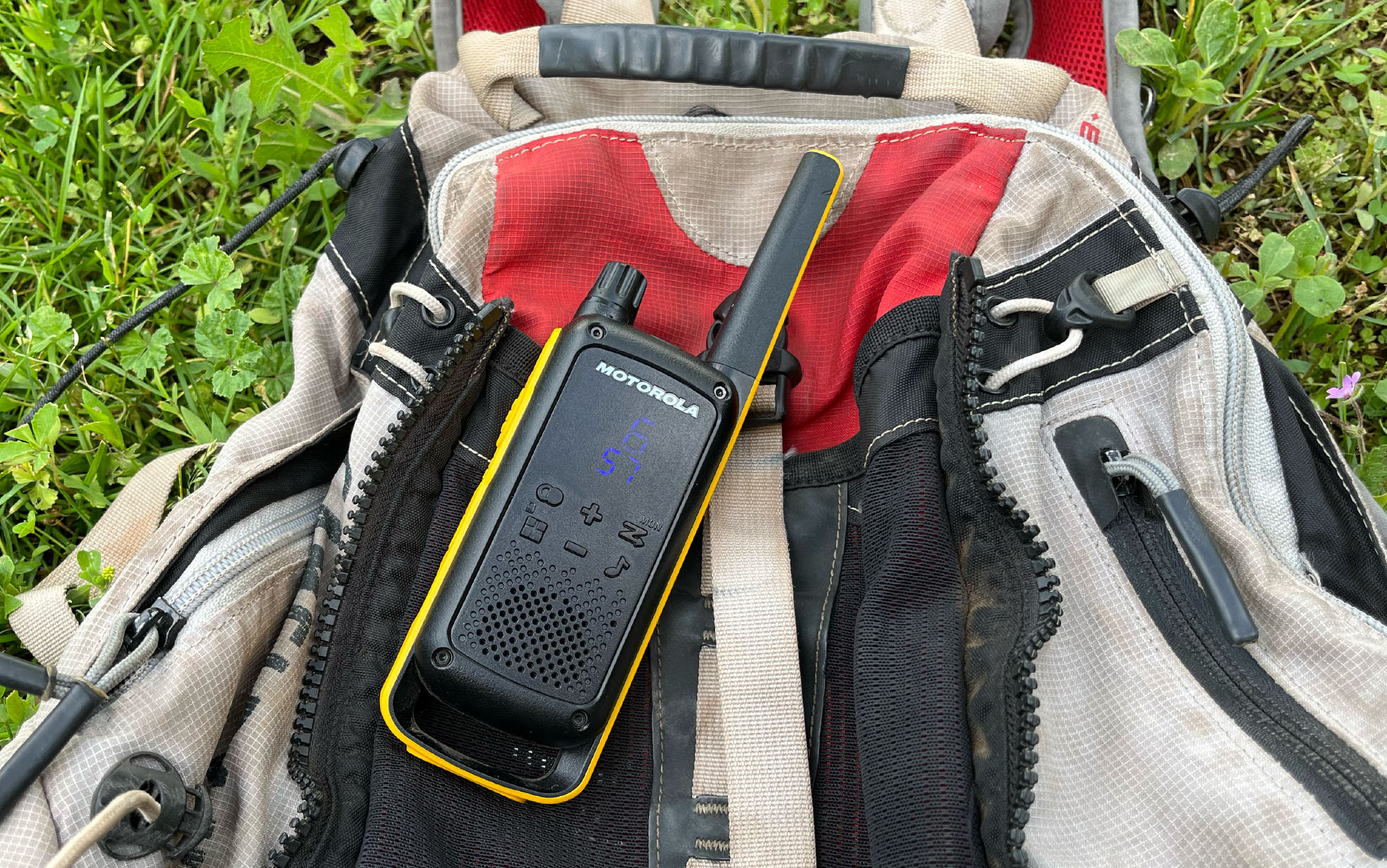 A walkie talkie is clipped to a day pack.