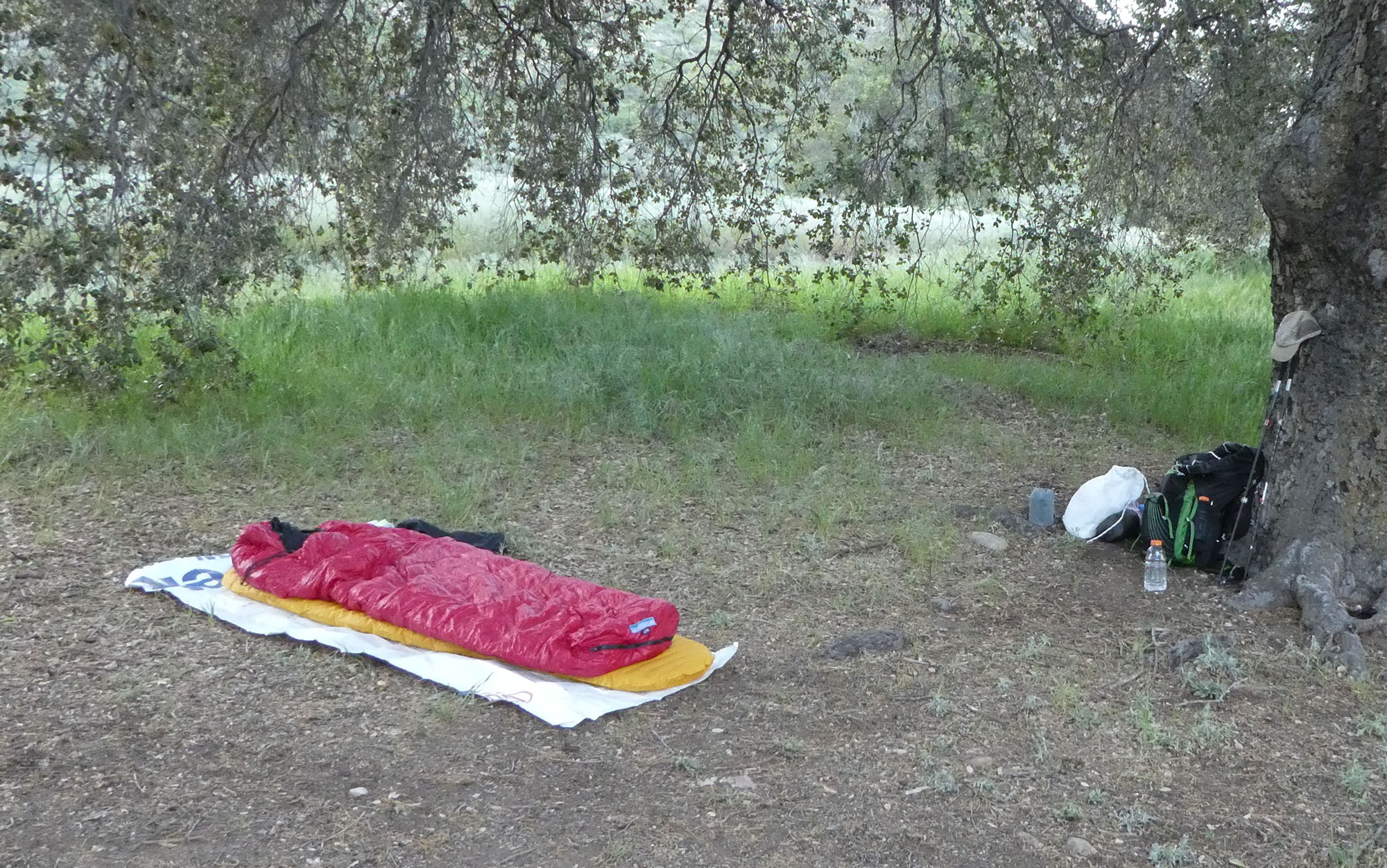 A tent footprint lies under a sleep system.