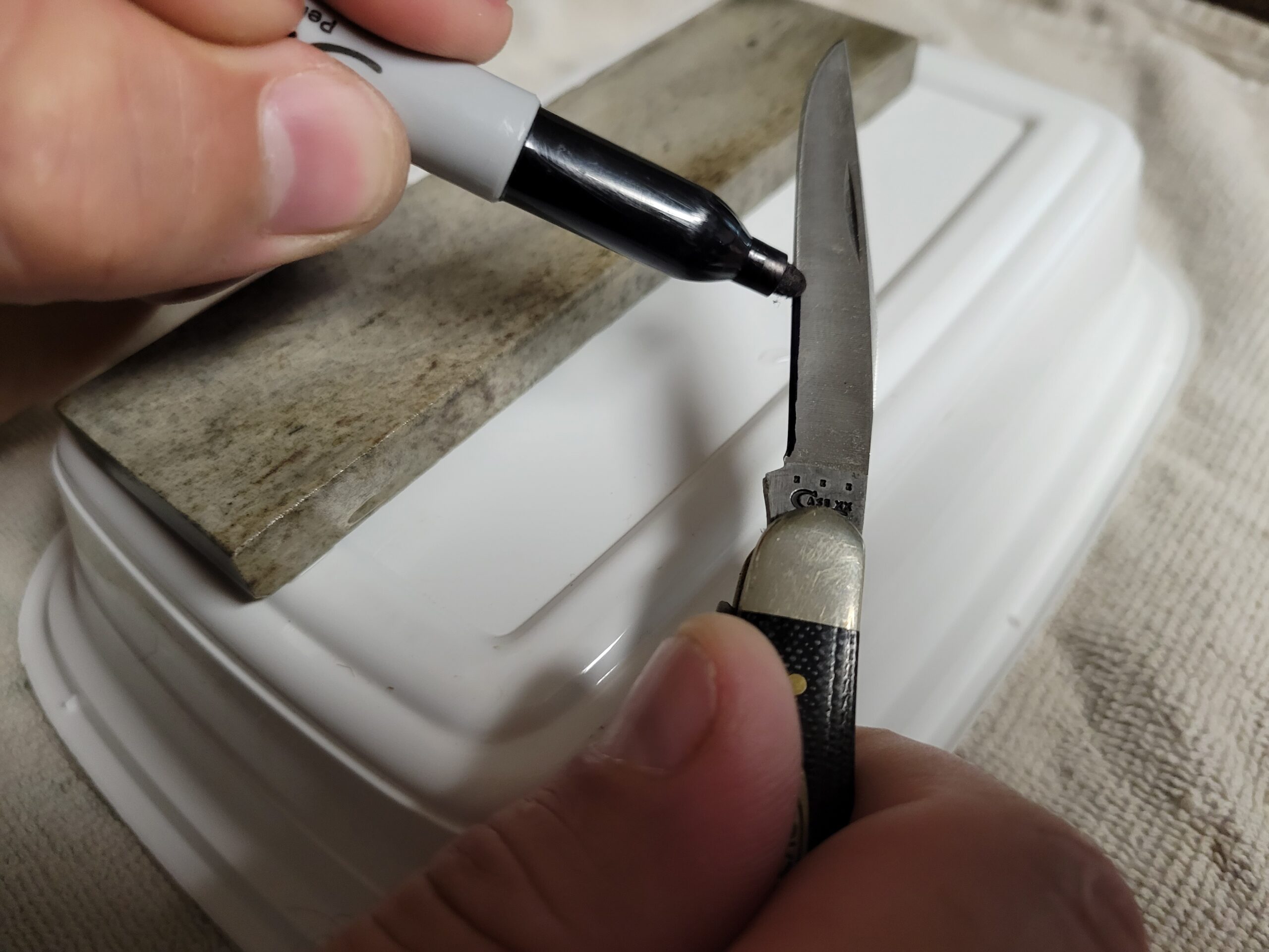 Marking the edge of a pocket knife to find the proper sharpening angle.