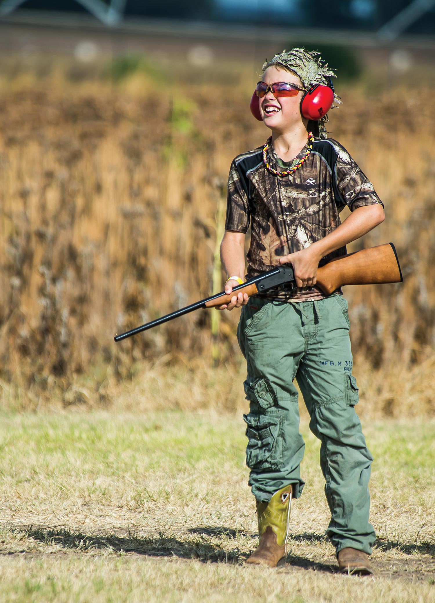 Young hunter with safety glasses and ear muffs holds single-shot shotgun.