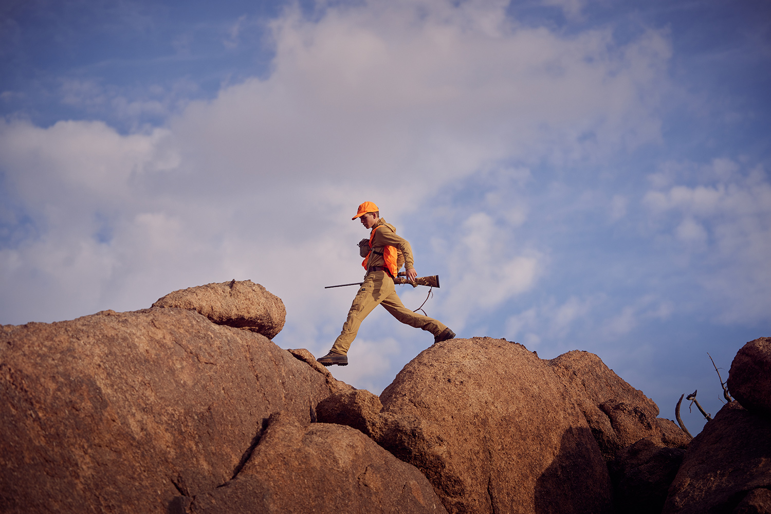 young hunter strides across tops of large rocks
