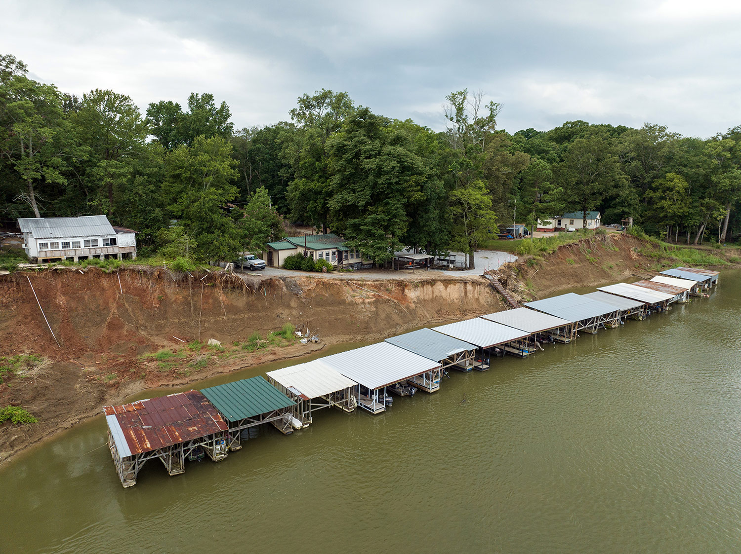 Docks on the White River, Arkansas, in front of eroded riverbank. Houses in the background.