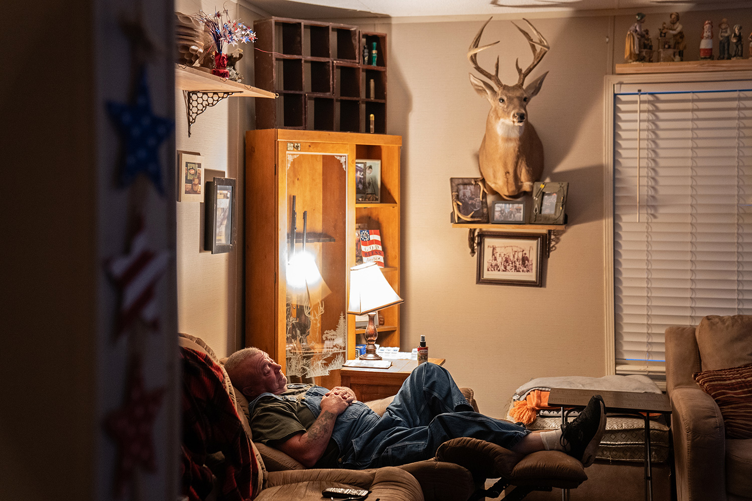 man naps in living room with deer head, photos