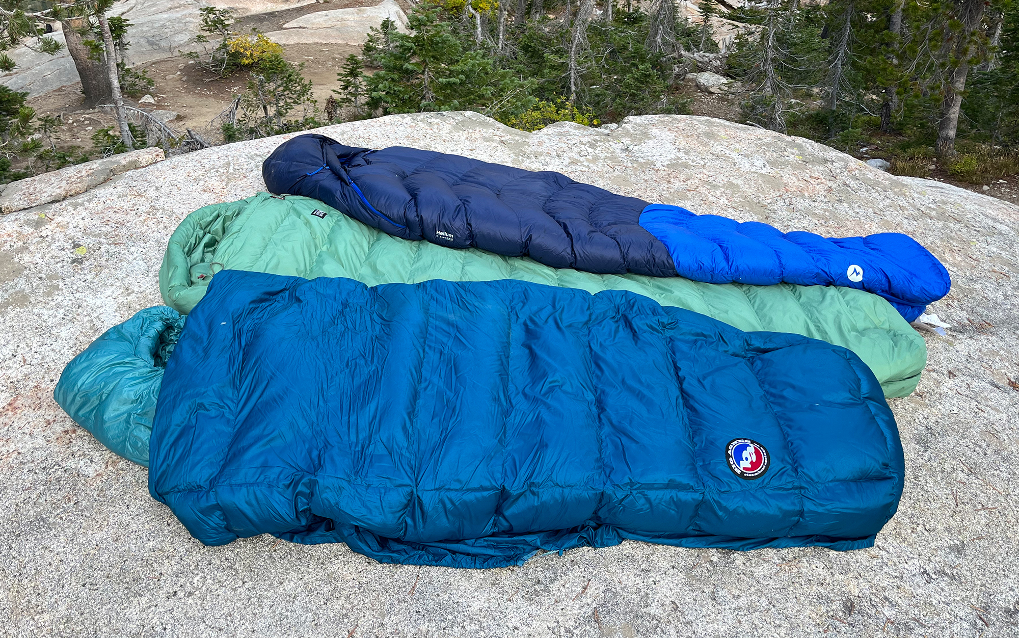 Three of the best sleeping bags lay on a rock.