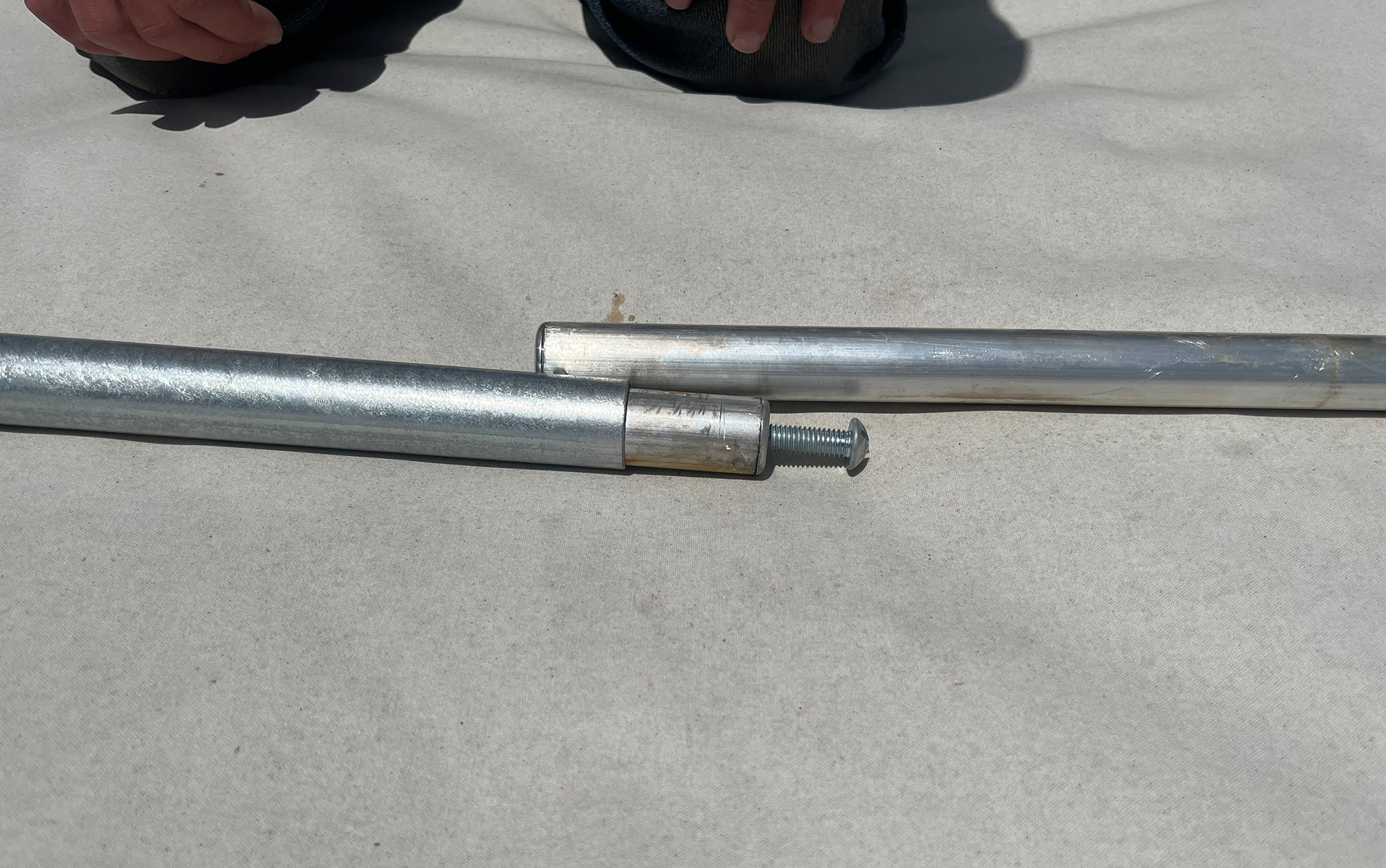 To tension the ridge pole responsible for keeping the roof taut, insert the screw into its mate and push down. Then slide the steel tube overtop to secure the spring bar.