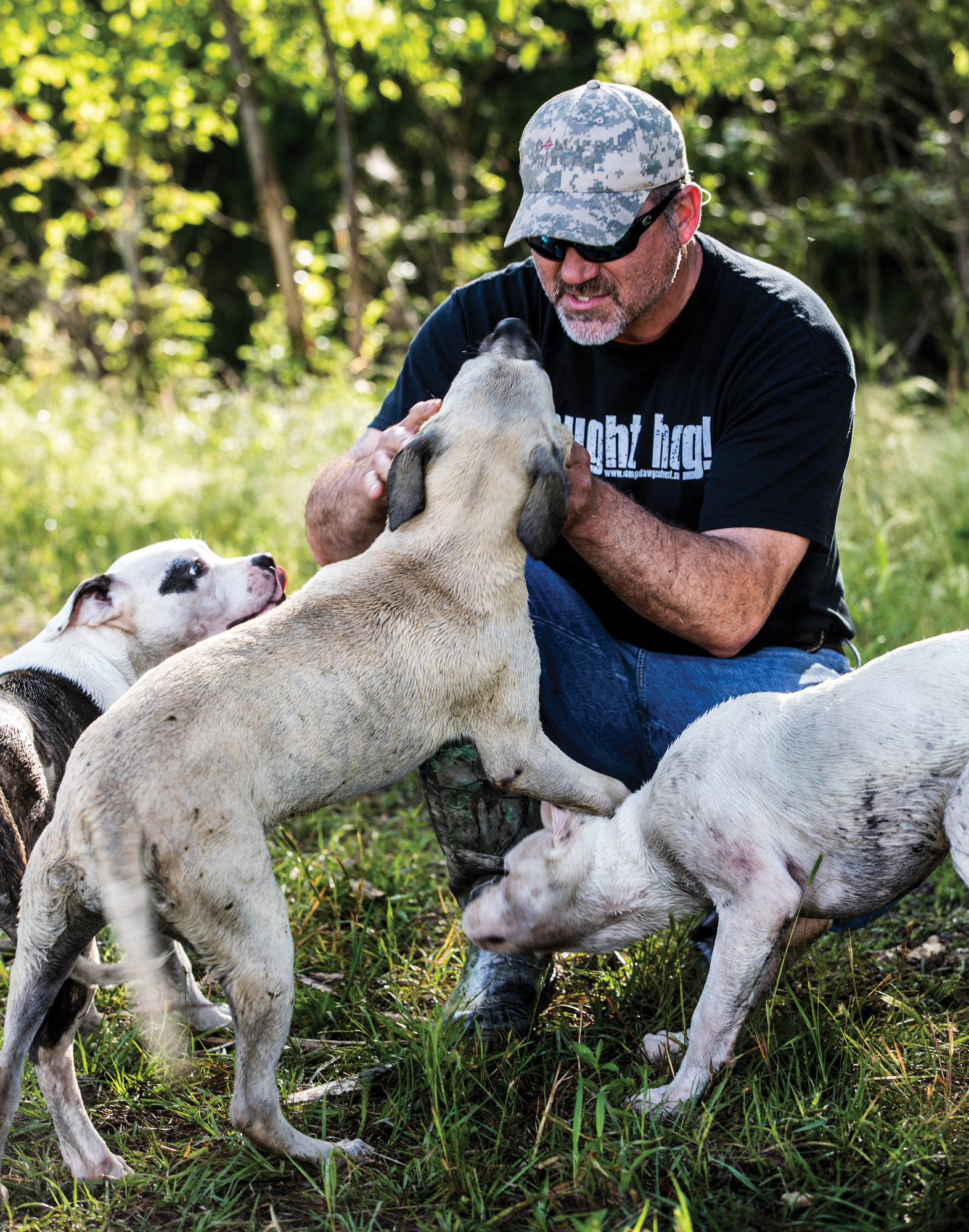 A hunter pets his hog puppies.