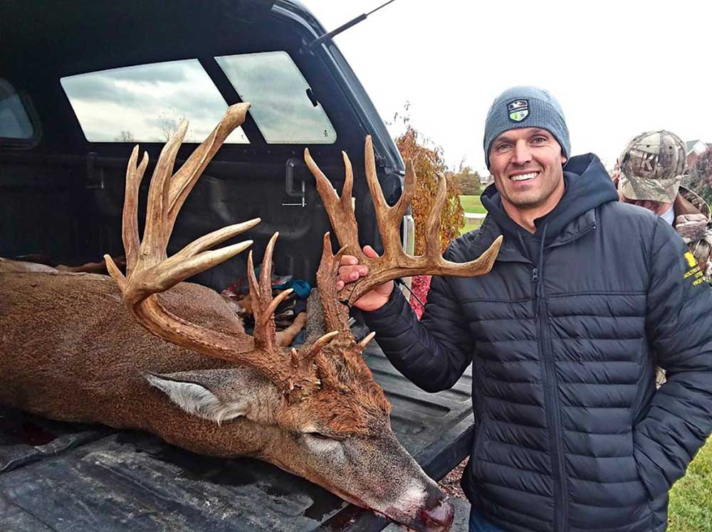 hunter standing next to giant buck