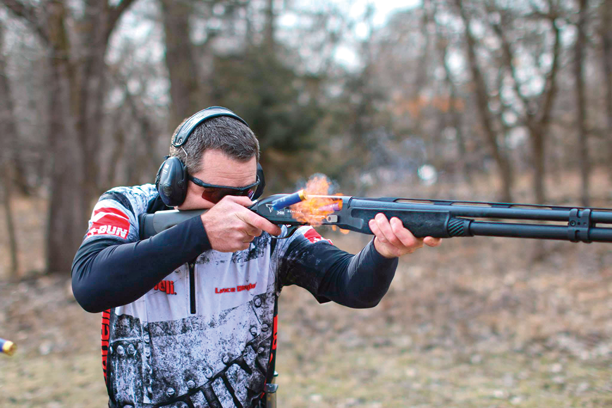 Competition skeet shooter with black semi-auto shotgun, fire, and shells ejecting from the action.
