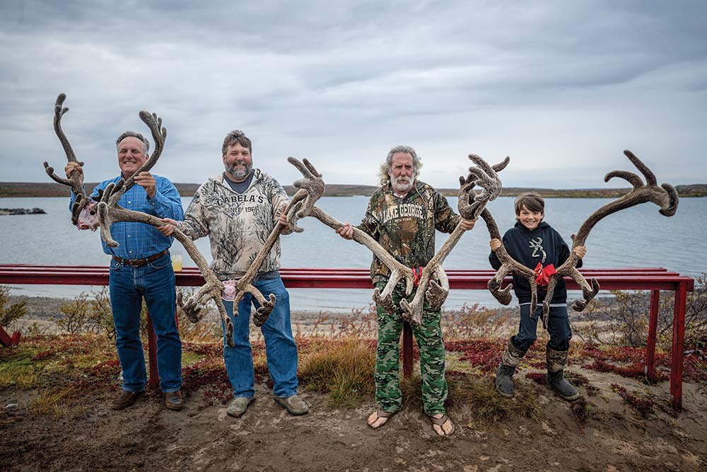 four hunters holding up caribou antlers