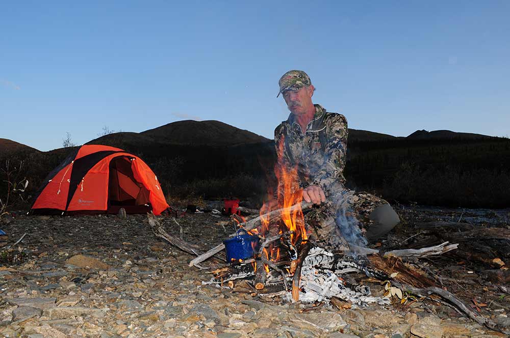 hunter tending a fire at an alaskan hunt