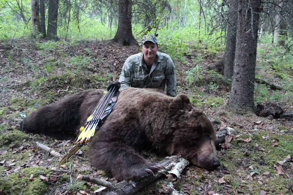 a hunter kneeling next to a bear