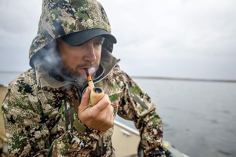 man wearing camouflage smoking a pipe
