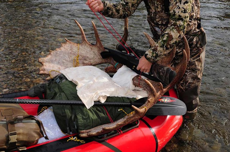 hunter standing in a stream with a packraft