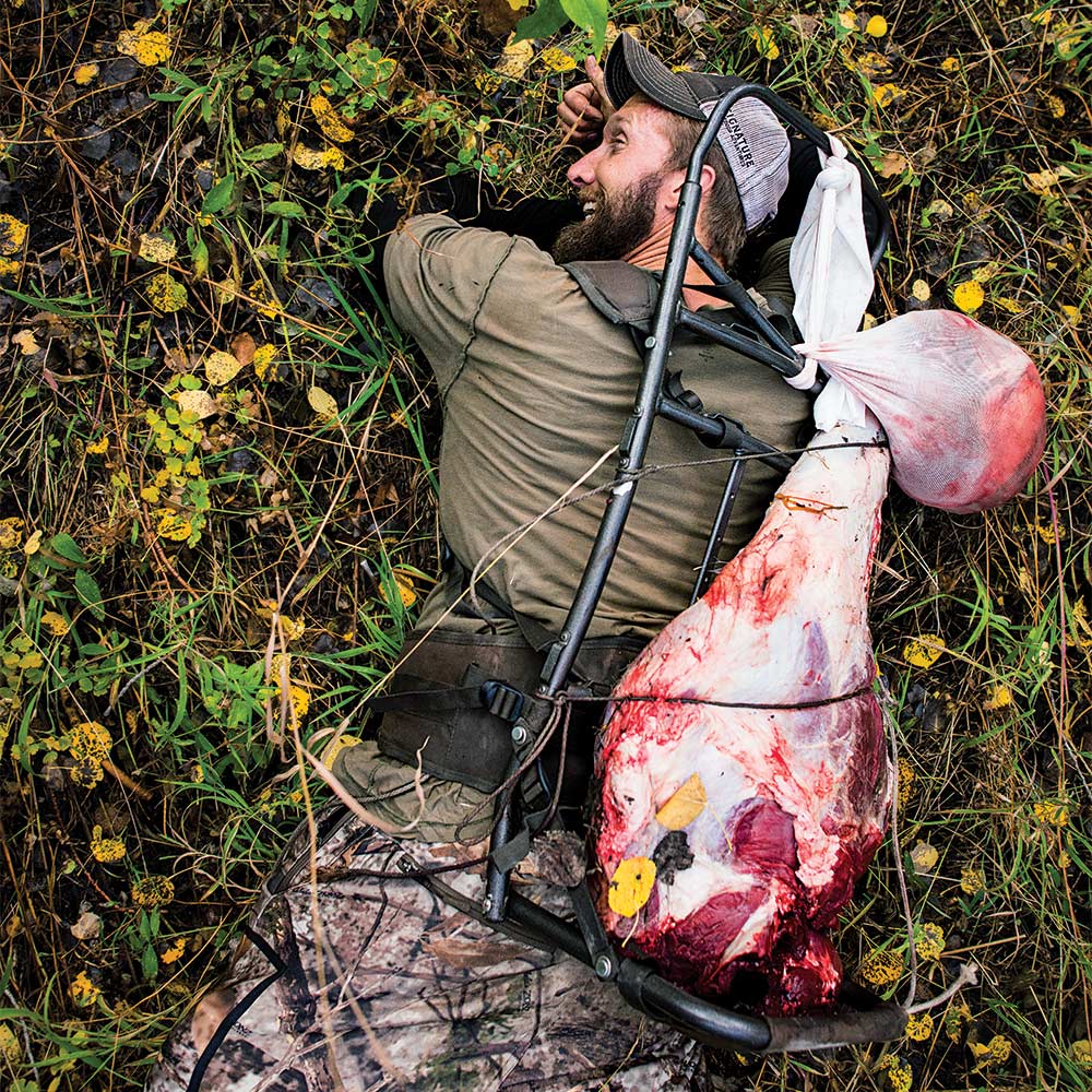 hunter on ground carrying elk meat