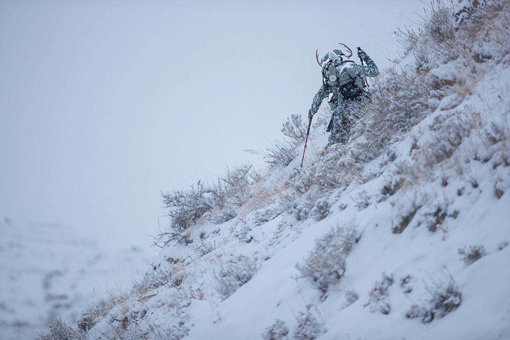 hunter hauling whitetail up snow hillside