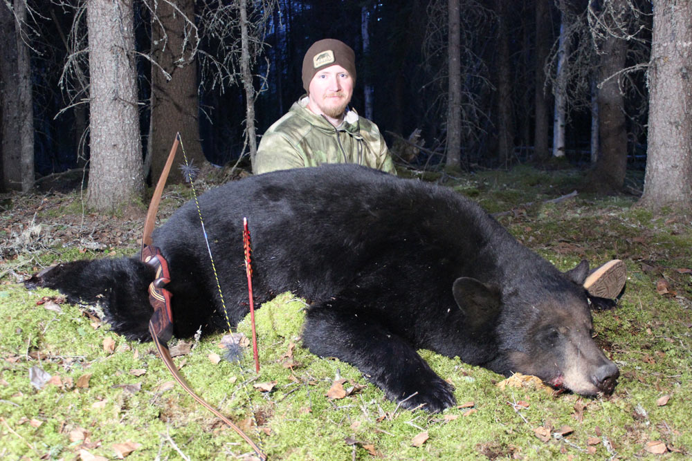 hunter kneeling next to a bear
