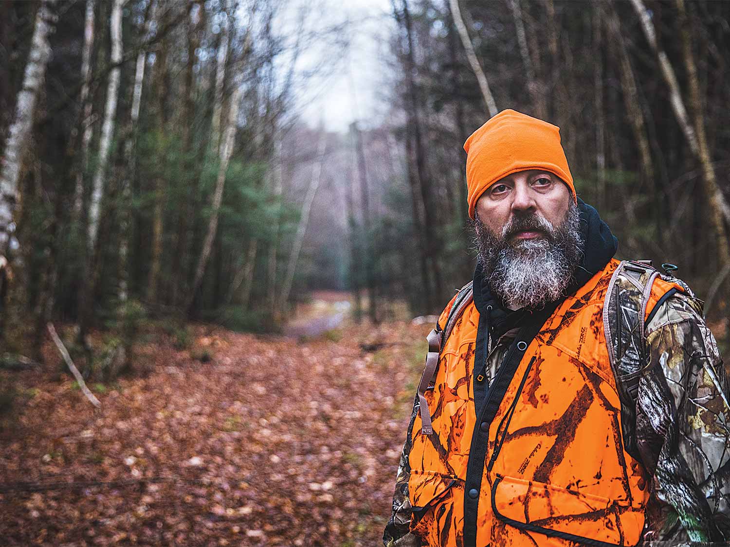 hunter in orange standing in the woods
