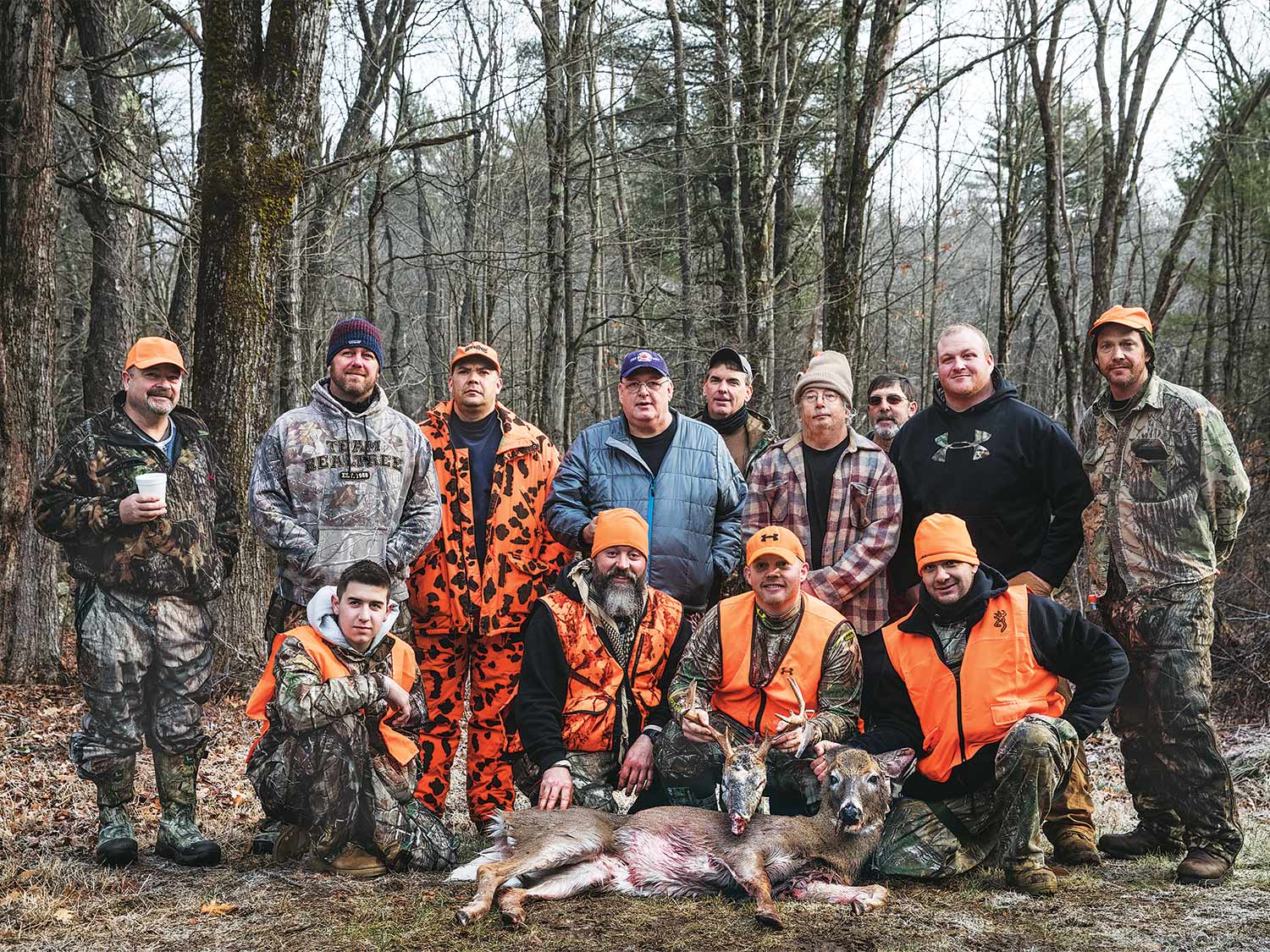 group of male hunters standing over a deer