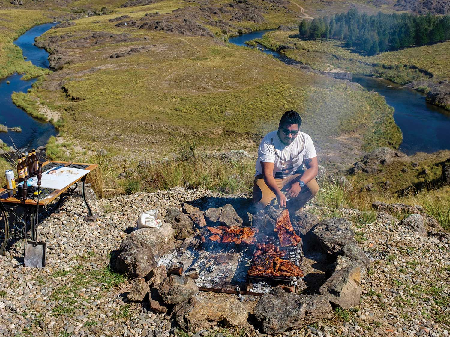 man cooking red stag on a campfire on the hillside of Argentina