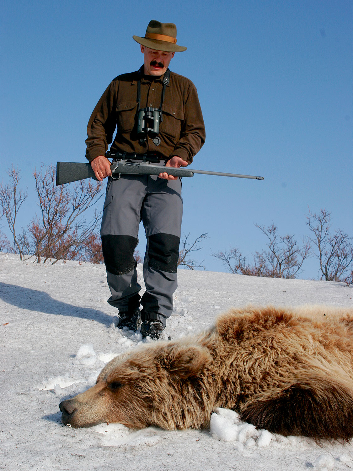 hunter and dead grizzly bear in the snow