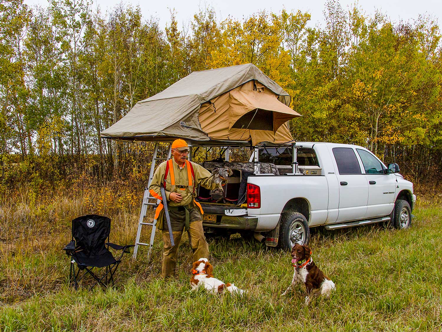 man with hunting dogs next to a truck and tent