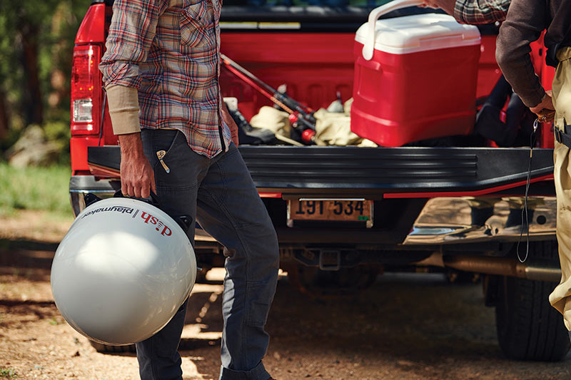 man carrying dish playmaker behind a truck