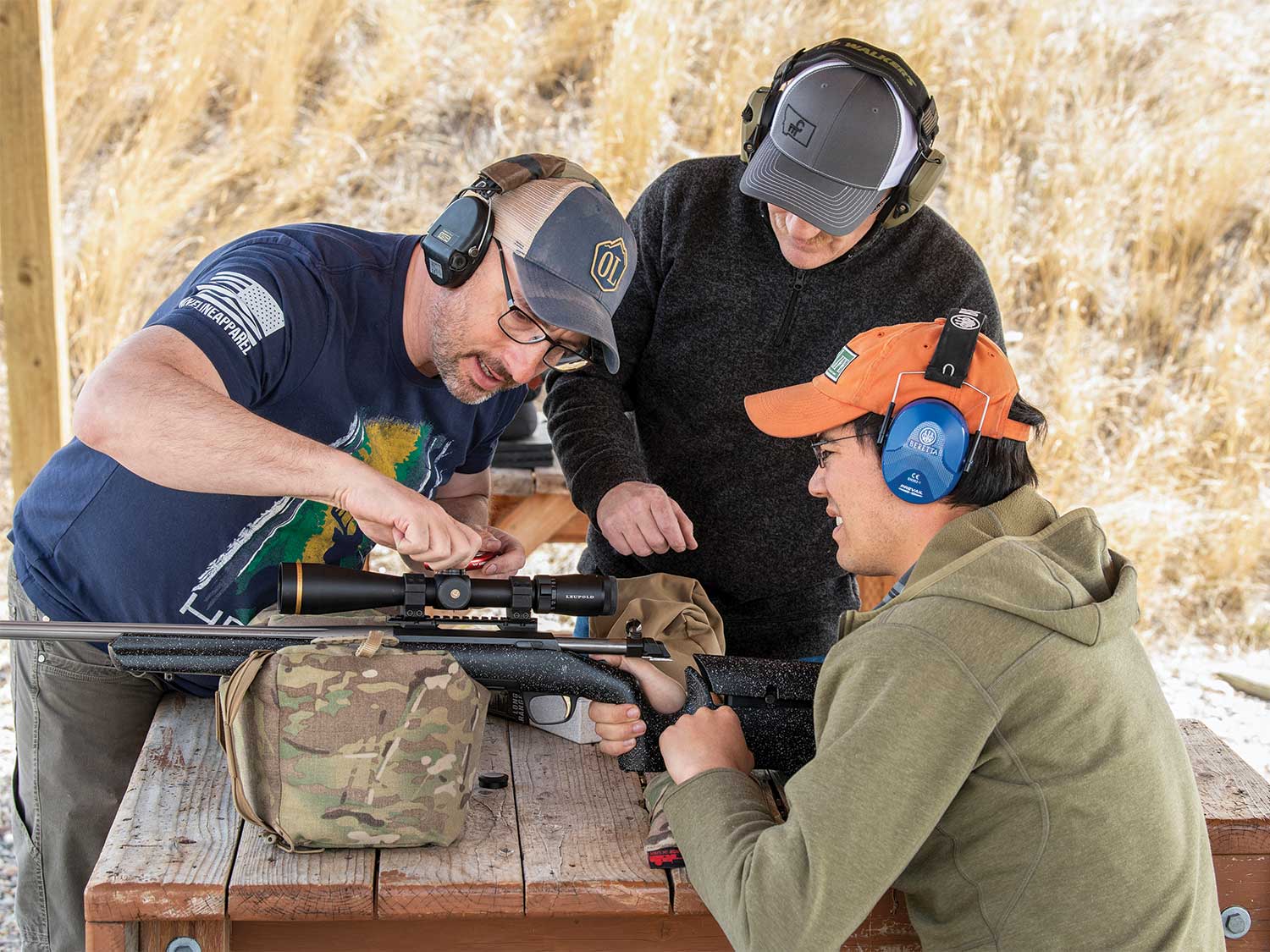 men adjusting rifle scope on rifle