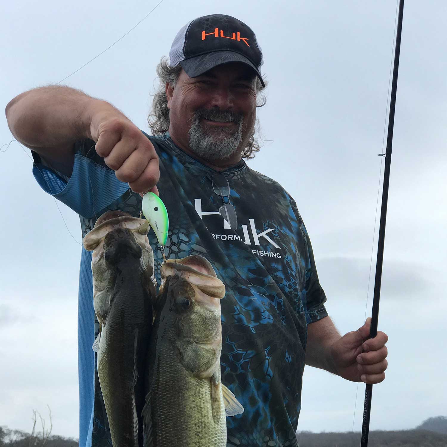 fisherman holding up a lure with two bass on it