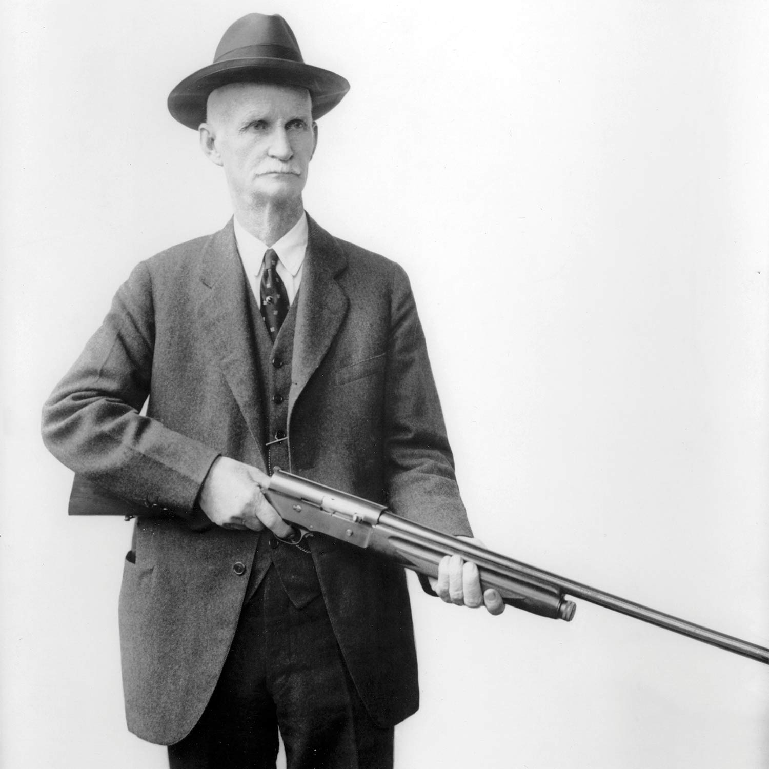 john moses browning holding an automatic-5 shotgun