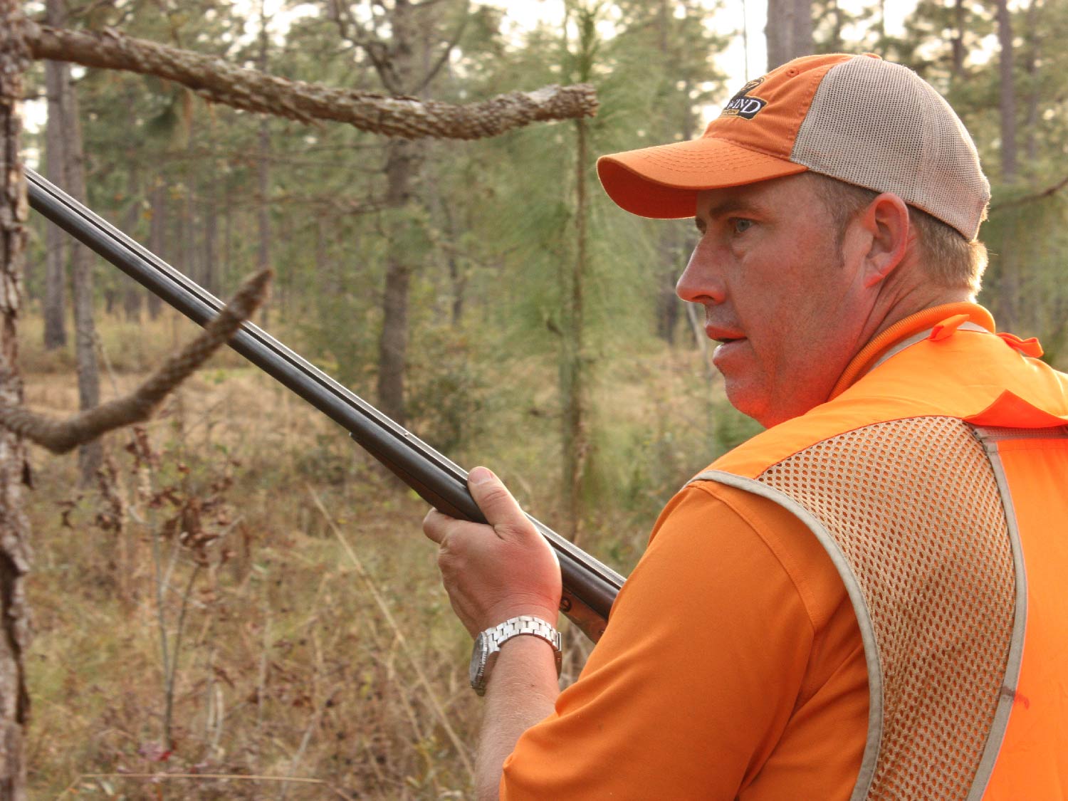 man in orange holding a shotgun