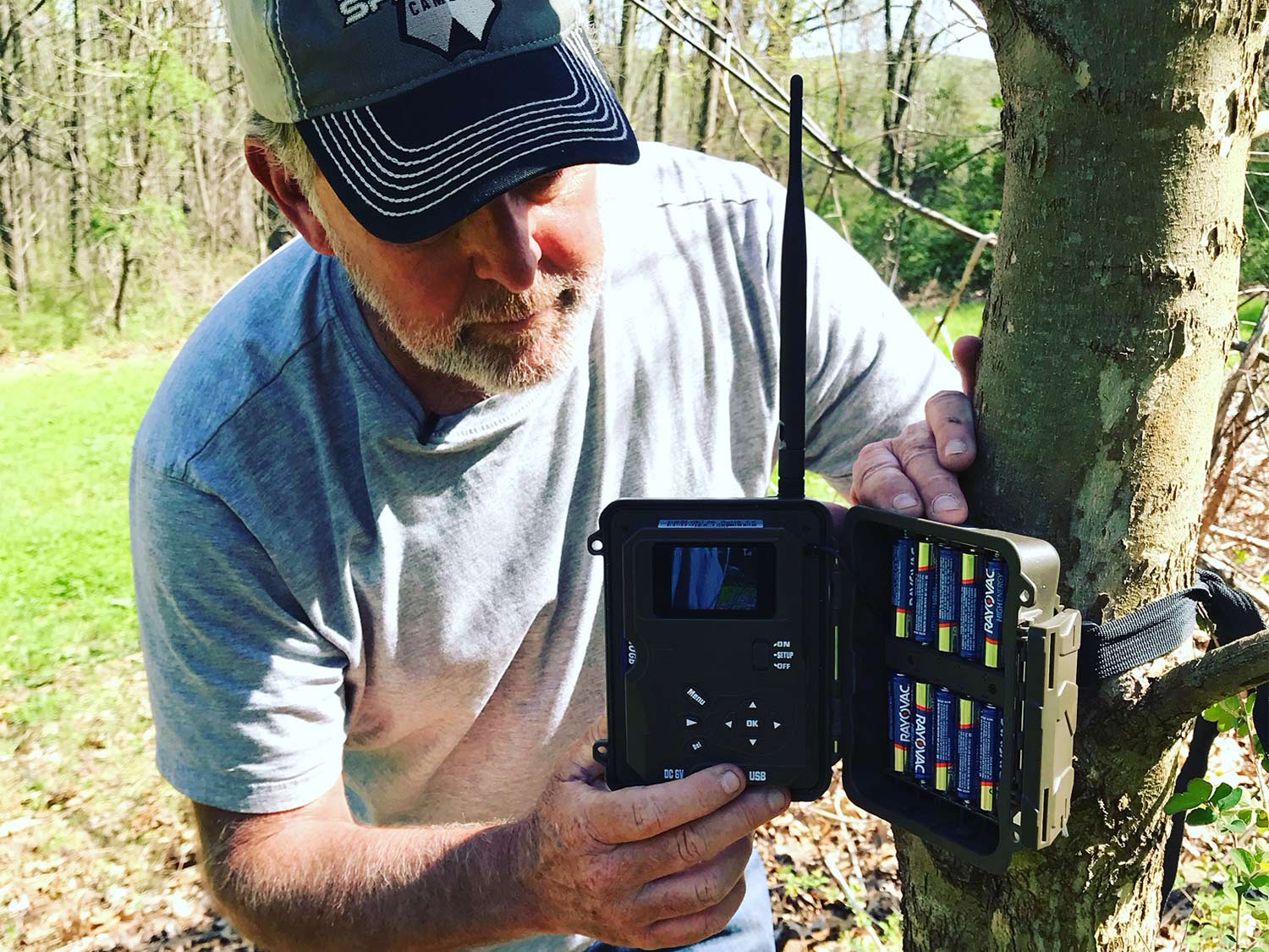 man installing trail cam on a tree