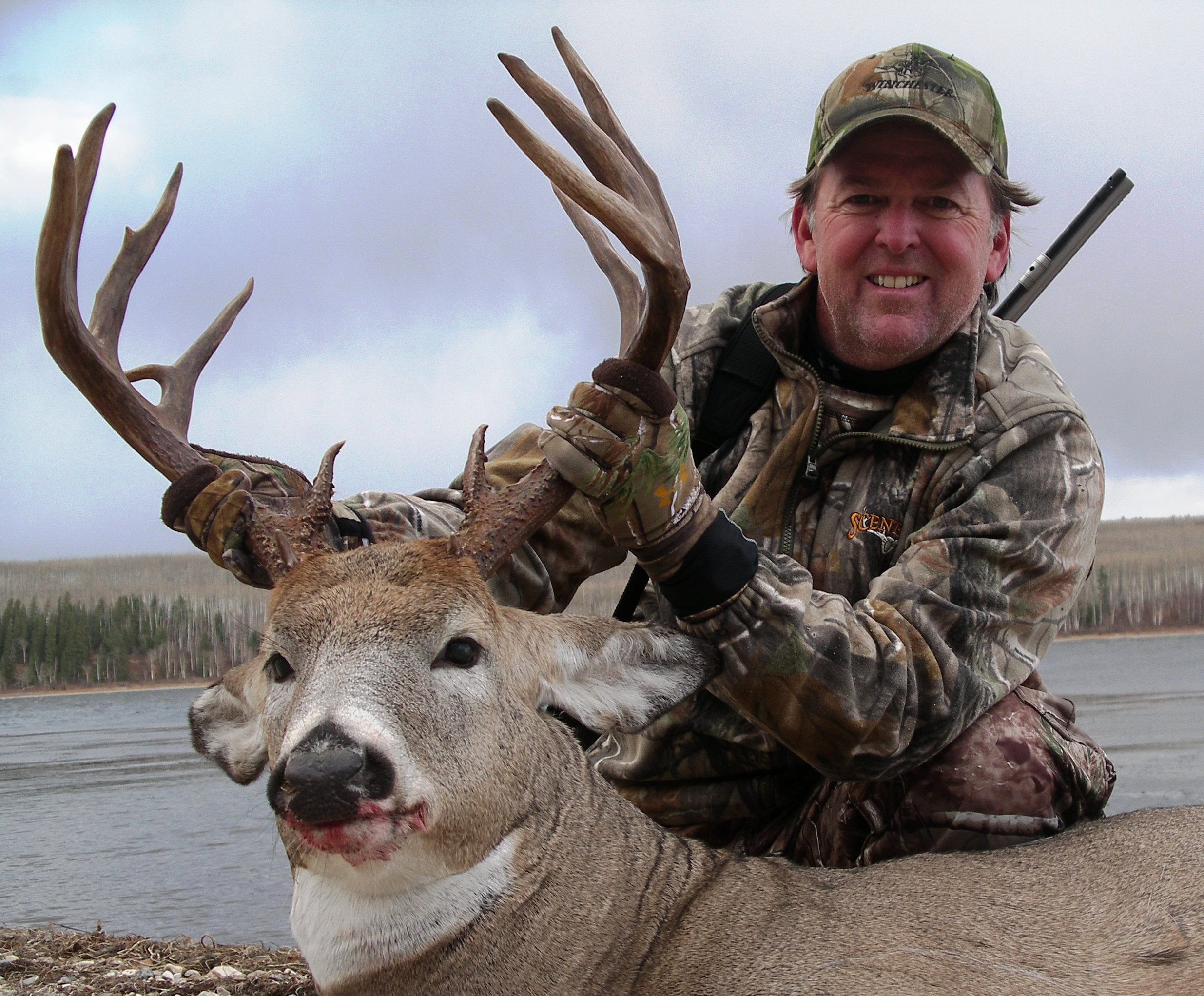 dead whitetail buck with hunter