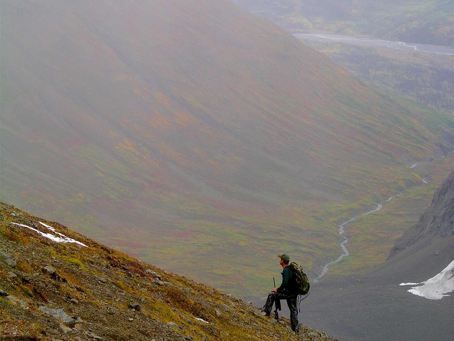 a hunter climbing a mountainside