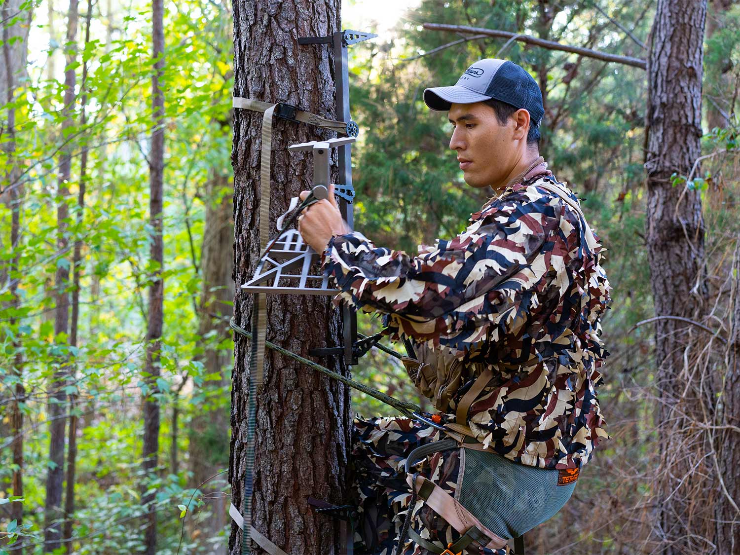 hunter hanging a tree saddle platform on a tree