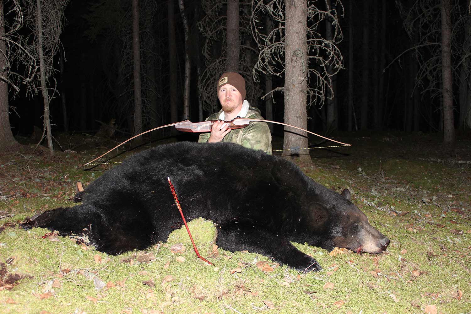 Tyler Freel kneeling behind a black bear.
