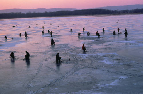 People Ice fishing on frozen lake.
